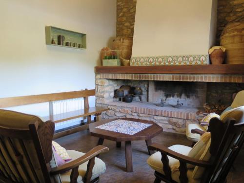 a living room with a fireplace and chairs and a table at Casa El Ros II - Turistrat in Vall dʼAlba