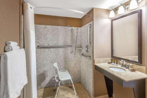 a bathroom with a sink and a shower and a chair at Wingate by Wyndham - St. George in St. George