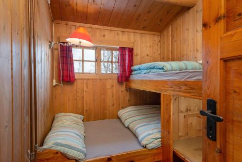2 Etagenbetten in einer Holzhütte mit einem Fenster in der Unterkunft Besseggen Fjellpark AS in Maurvangen