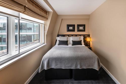 a bedroom with a bed and two windows at The Resident Victoria in London