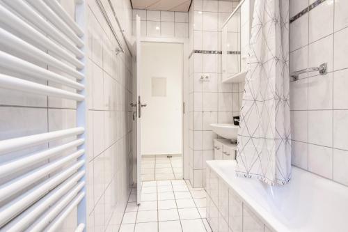 La salle de bains blanche est pourvue d'une baignoire et d'un lavabo. dans l'établissement E&K City Apartments, à Wuppertal