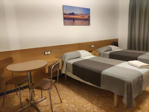 Cette chambre d'hôtel comprend deux lits, une table et des chaises. dans l'établissement Fonda Ca La Maria, à Avinyó