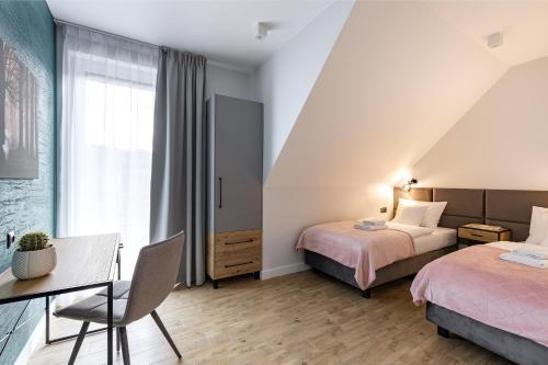 a hotel room with two beds and a table and chair at Śnieżka Exclusive Apartamenty in Kowary