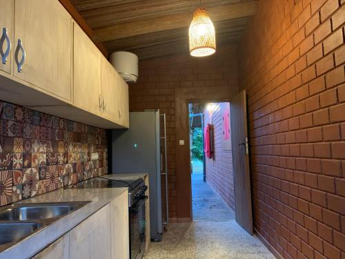 a kitchen with a sink and a brick wall at Natura luxury red house in Ouidah