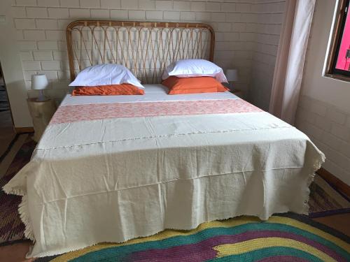 a bed with two pillows and a blanket on it at Natura luxury red house in Ouidah