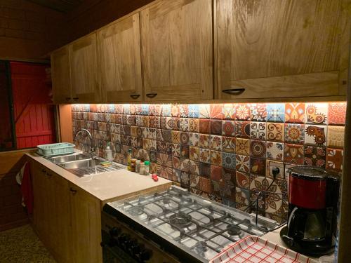 a kitchen with a sink and a tile wall at Natura luxury red house in Ouidah
