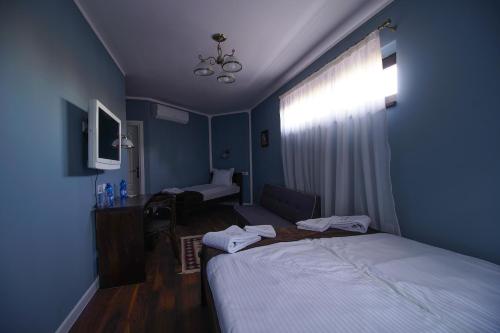 a bedroom with two beds and a desk and a window at Pulpudeva Family Hotel in Plovdiv