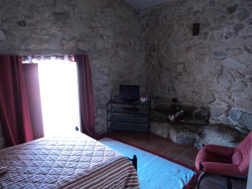 1 dormitorio con cama y pared de piedra en Casa Villar Mayor en Vilar Maior