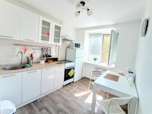 a kitchen with white cabinets and a table and a sink at Білі 1 кімнатні апартаменти Сіті- центр 4 поверх 9 поверхового будинку in Mykolaiv