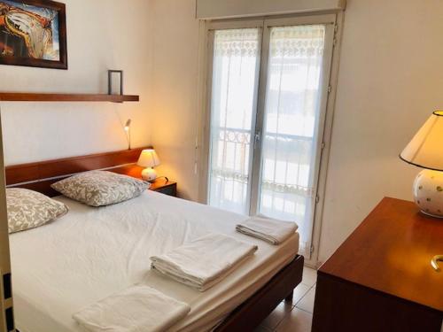 - une chambre dotée d'un lit blanc avec une lampe et une fenêtre dans l'établissement Appartement Palais des Dômes avec piscine, à Nice