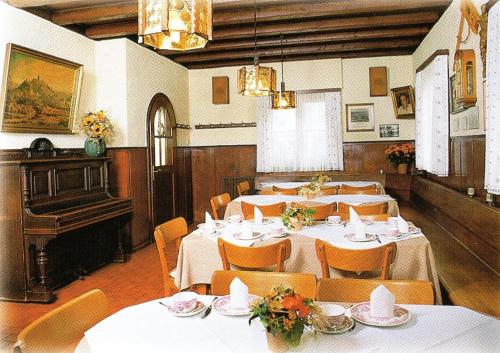 a dining room with tables and chairs and a piano at Gasthof Lamm in Beilstein
