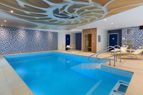 a swimming pool with a ceiling with a large blue swimming pool at Citadines Confluent Nantes in Nantes