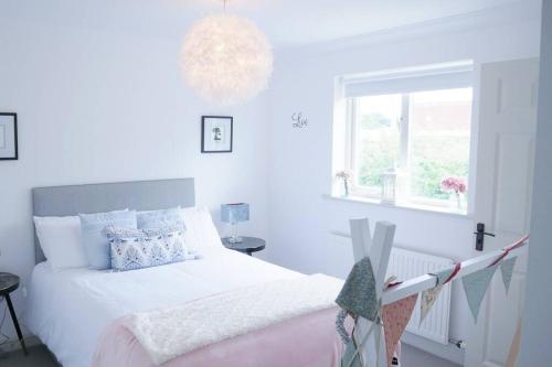 a white bedroom with a bed and a window at The Croft a lovely town house in the centre of Holt with free PARKING for two cars in Holt