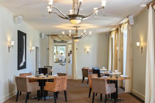 a dining room with tables and chairs and a chandelier at Hôtel Résidence Parc des Eaux Vives in Geneva
