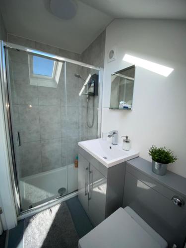 uma casa de banho branca com um chuveiro e um lavatório. em Coalhouse Apartment em Seaham