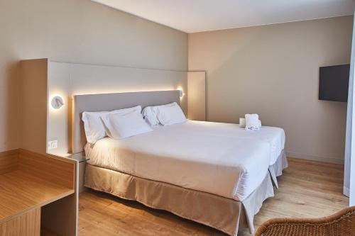 een slaapkamer met een wit bed en een televisie bij Silken Reino de Aragón in Zaragoza