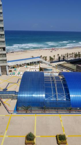 a blue building next to a beach with the ocean at Sea View Deluxe in Bat Yam