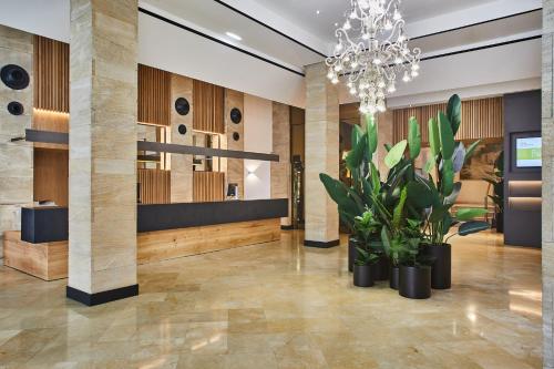 a lobby with potted plants and a chandelier at Silken Reino de Aragón in Zaragoza