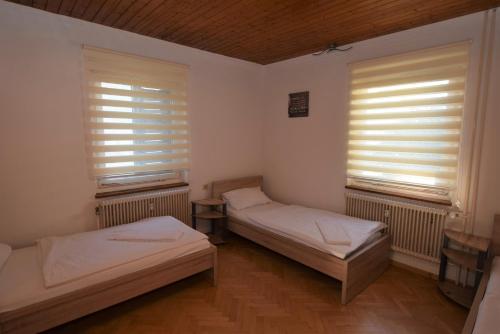 two beds in a room with two windows at Apartment Nürtingen Zentrum in Nürtingen