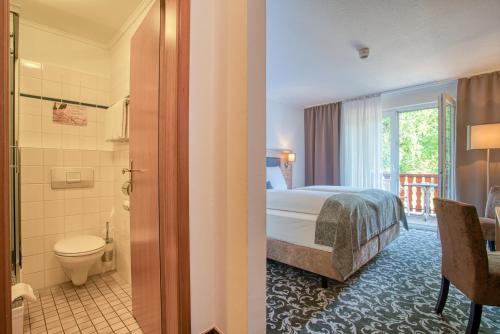 バート・ベヴェンセンにあるSporthotel Bad Bevensenのベッドとバスルーム付きのホテルルームです。