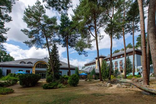 a building with trees in front of it at 4 Pory Roku Resort Sauna & Spa in Bąkowo