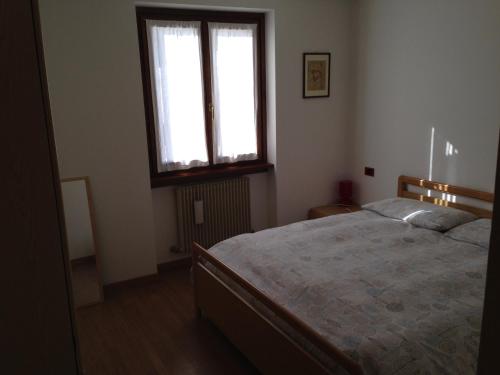 a bedroom with a bed and a window at Chalet Madonna di Campiglio CIPAT ZERO22143-AT-ZERO69206 in Madonna di Campiglio