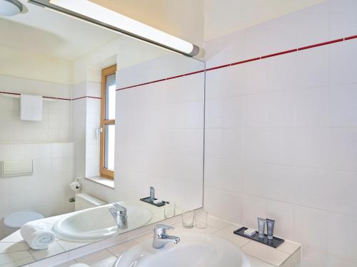 a white bathroom with two sinks and a mirror at Hapimag Ferienwohnungen Braunlage in Braunlage