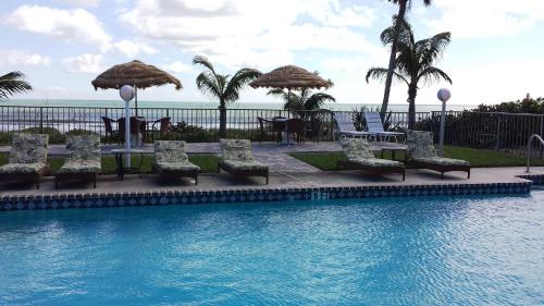 a swimming pool with chairs and tables and umbrellas at Surf Studio Beach Resort in Cocoa Beach