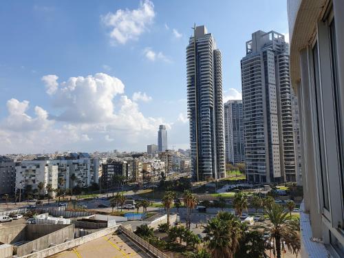 a view of a city with tall buildings and palm trees at Sea View Deluxe in Bat Yam