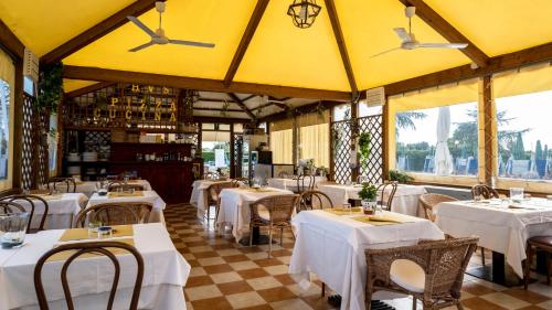 a restaurant with white tables and chairs and windows at Hotel Villa Sara in Mestre