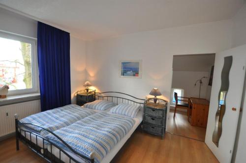 sypialnia z łóżkiem z niebieską kołdrą i oknem w obiekcie Ferienwohnungen Abraham w Lubece