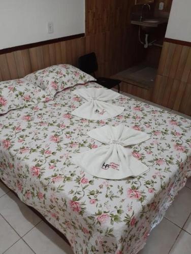 uma cama com flores num quarto em Hotel Hospedaria Albert em Cachoeiro de Itapemirim