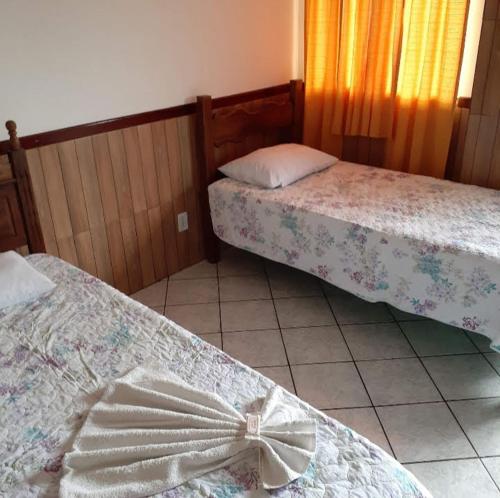 um quarto com duas camas com um laço em Hotel Hospedaria Albert em Cachoeiro de Itapemirim