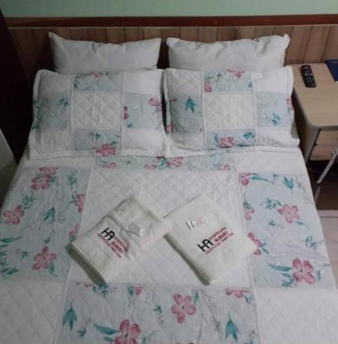 uma cama com toalhas e almofadas em Hotel Hospedaria Albert em Cachoeiro de Itapemirim