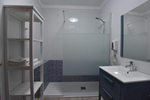uma casa de banho branca com um chuveiro e um lavatório. em Monte das Galhanas em Monte do Pigeiro