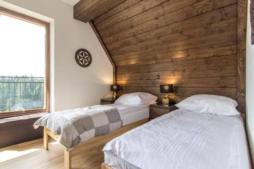 2 łóżka w pokoju z drewnianą ścianą w obiekcie Apartamenty Liptowskie Hale Zakopane w mieście Kościelisko