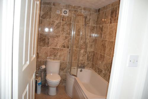 a bathroom with a tub and a toilet and a sink at One Bedroom Flat, Granary Road in Ponders End