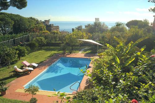 a swimming pool in a garden with a view of the ocean at Magnificent Villa Sanremo in Sanremo