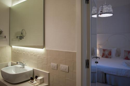 a bathroom with a sink and a mirror and a bed at La Peschiera in Savelletri di Fasano