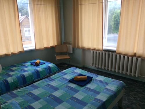 a bedroom with two beds and a chair and windows at Hermes Külalistemaja in Võru