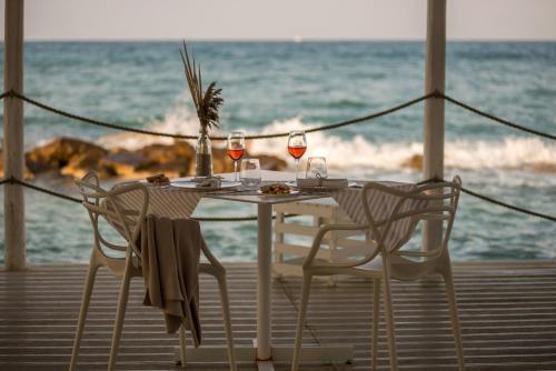 a table with two chairs and wine glasses on the beach at La Peschiera in Monopoli