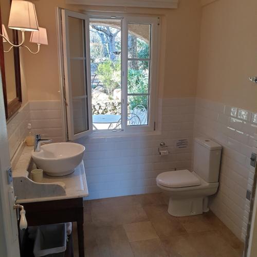 a bathroom with a toilet and a sink and a window at Domaine du Bois d'Amont in Cabris