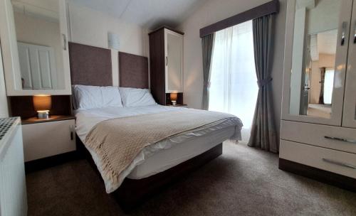 um quarto com uma cama grande e uma janela em Sea Shore Lodge Mudeford em Christchurch
