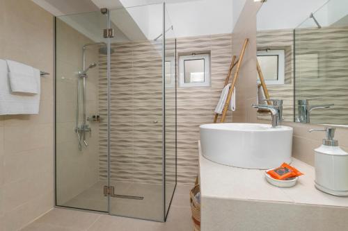 a bathroom with a glass shower and a sink at V&C Paradise Apartments in Rodakino