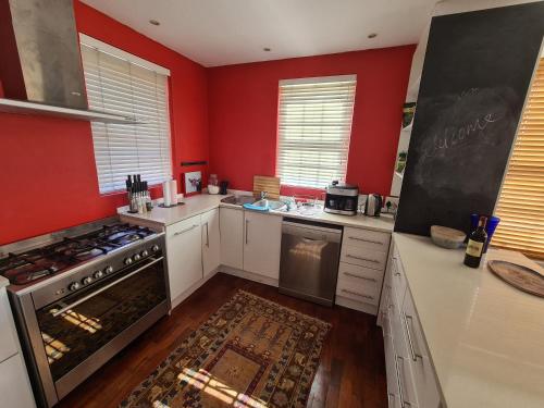 a kitchen with red walls and a stove top oven at Table Mountain View Villa in Cape Town