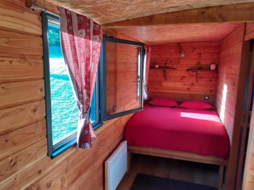 1 dormitorio en una cabaña de madera con cama y ventana en La Roulotte de la Clef des Champs en Buzancy