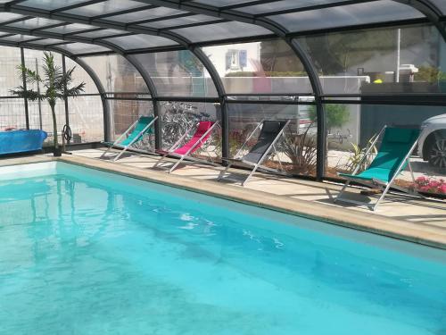 a group of chairs sitting next to a swimming pool at Gite LES BALISES- BABORD-Maisons de bord de mer avec spa -SAINT GILLES CROIX DE VIE - 27 Avenue NOTRE DAME in Saint-Gilles-Croix-de-Vie
