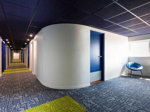 a corridor of an office with blue ceilings and a blue chair at ibis budget Bordeaux Centre - Gare Saint Jean in Bordeaux