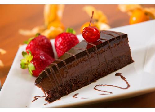 a piece of chocolate cake with strawberries on a plate at Leques Brasil Hotel Escola in Sao Paulo