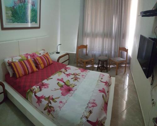 a bedroom with a bed and a tv and chairs at Sea View Deluxe in Bat Yam